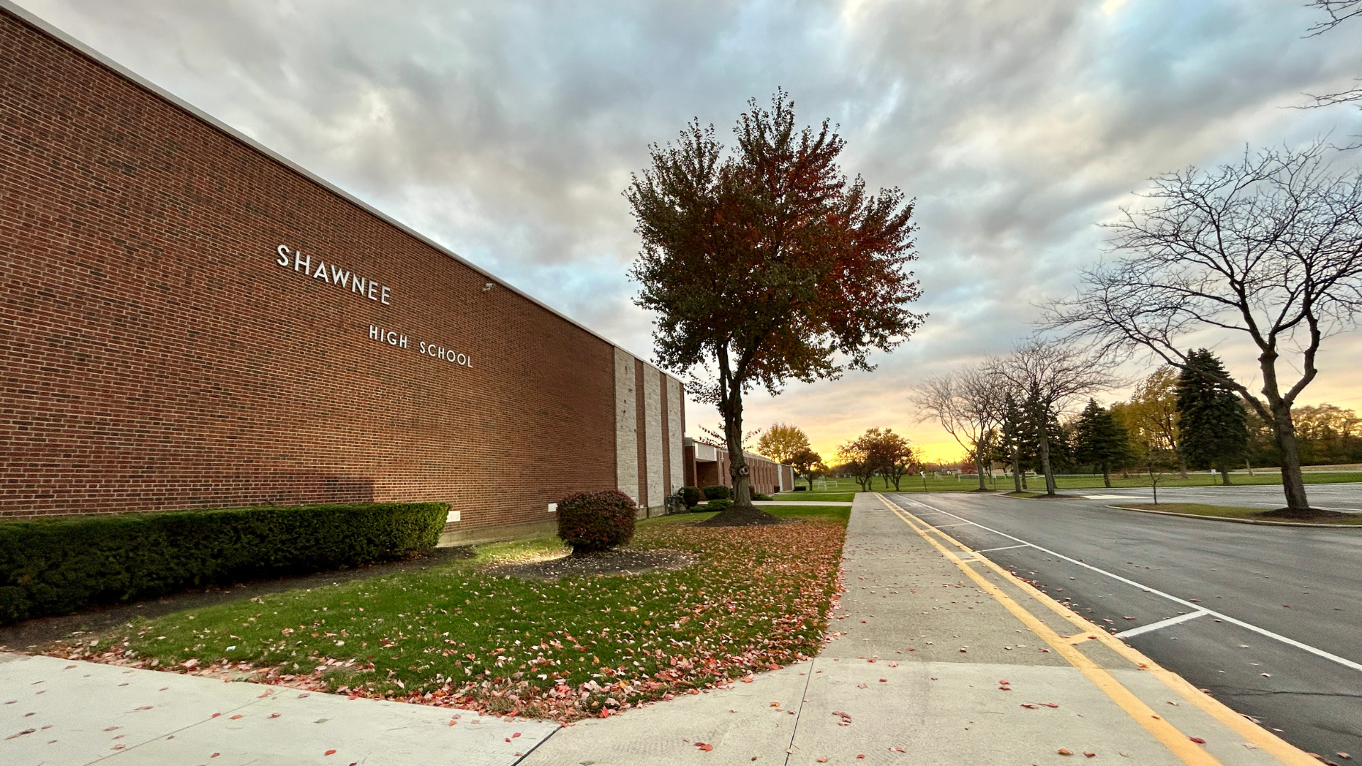 Picture of Shawnee High School building with bricks of varying shades of brown plus a tree, blue sky, and white clouds