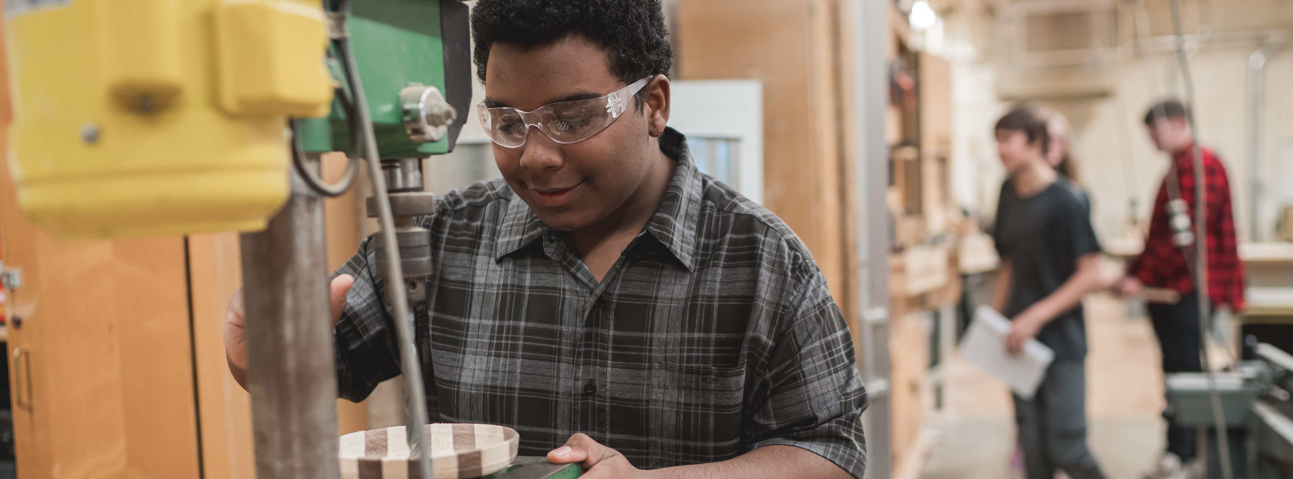 Student making a project using a drill press