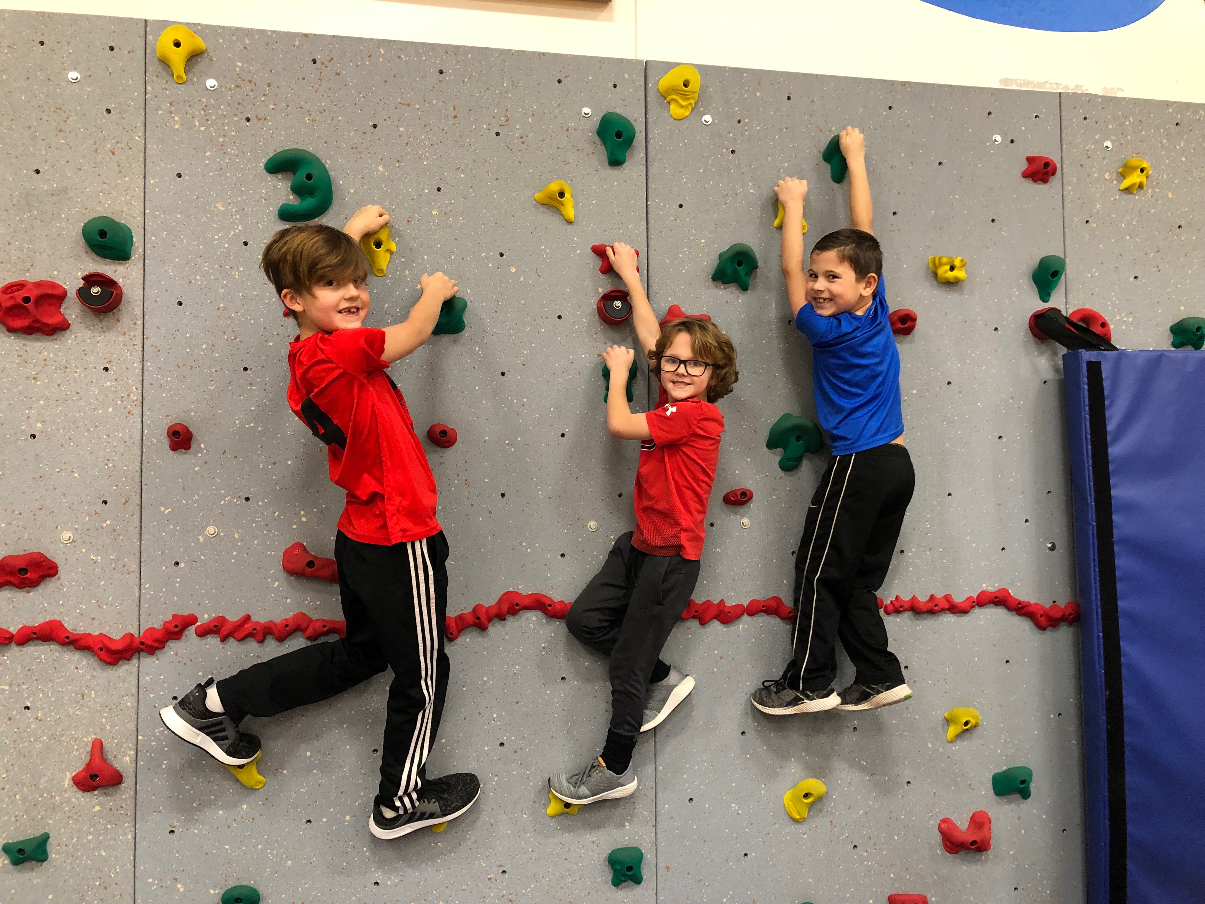 Three students practicing on a mountain climbing wall