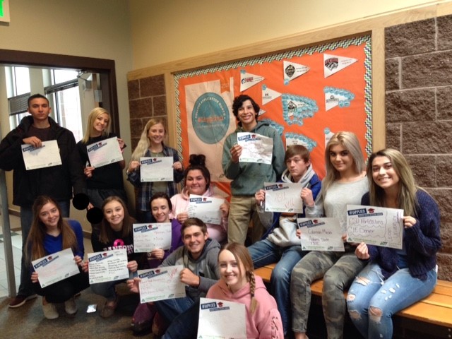 photo of students holding up papers in front of bulletin board