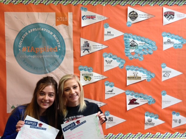 photo of two girls holding up papers in front of a bulletin board