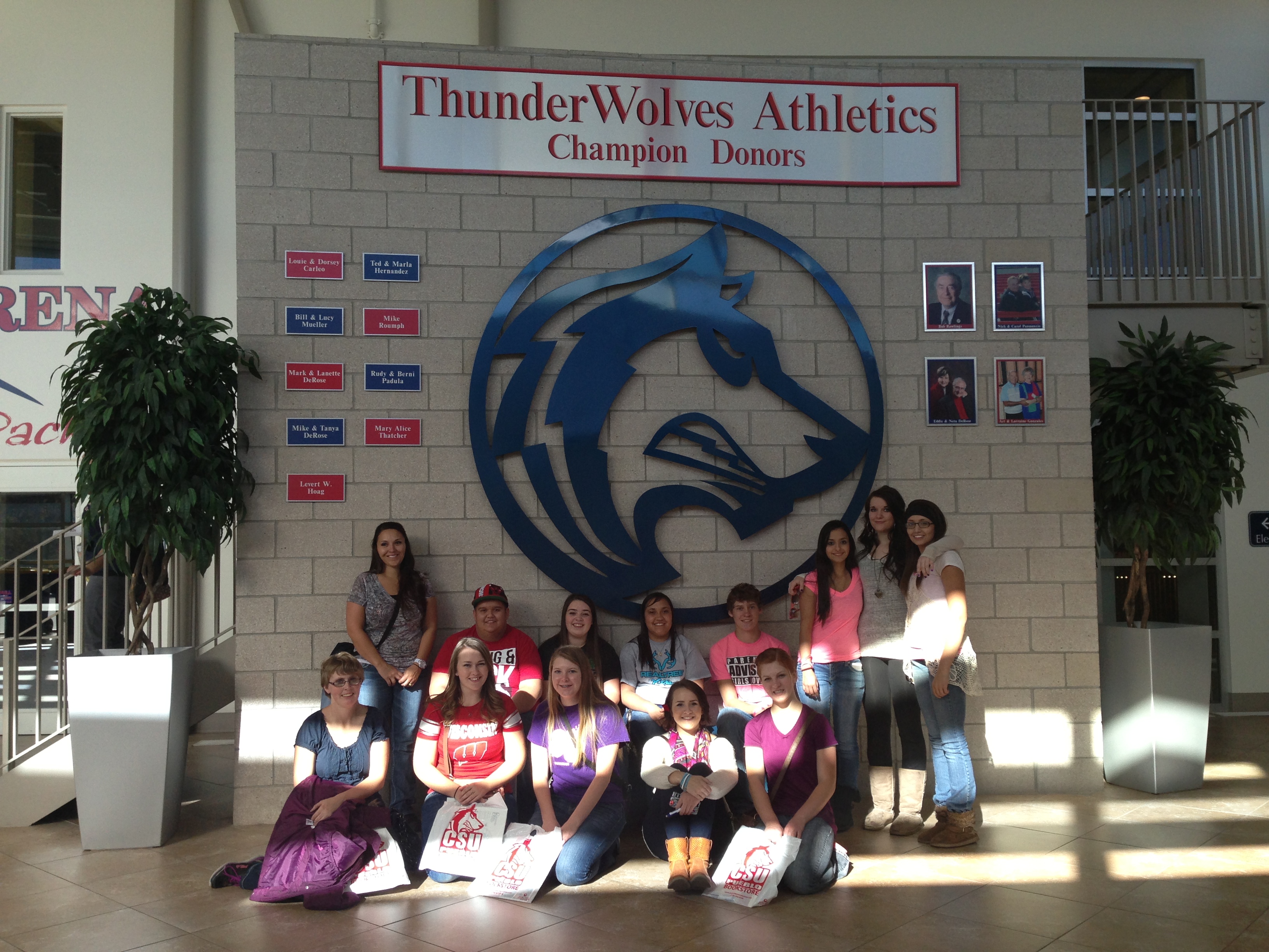 photo of a group of students in front of a wolf logo on a wall