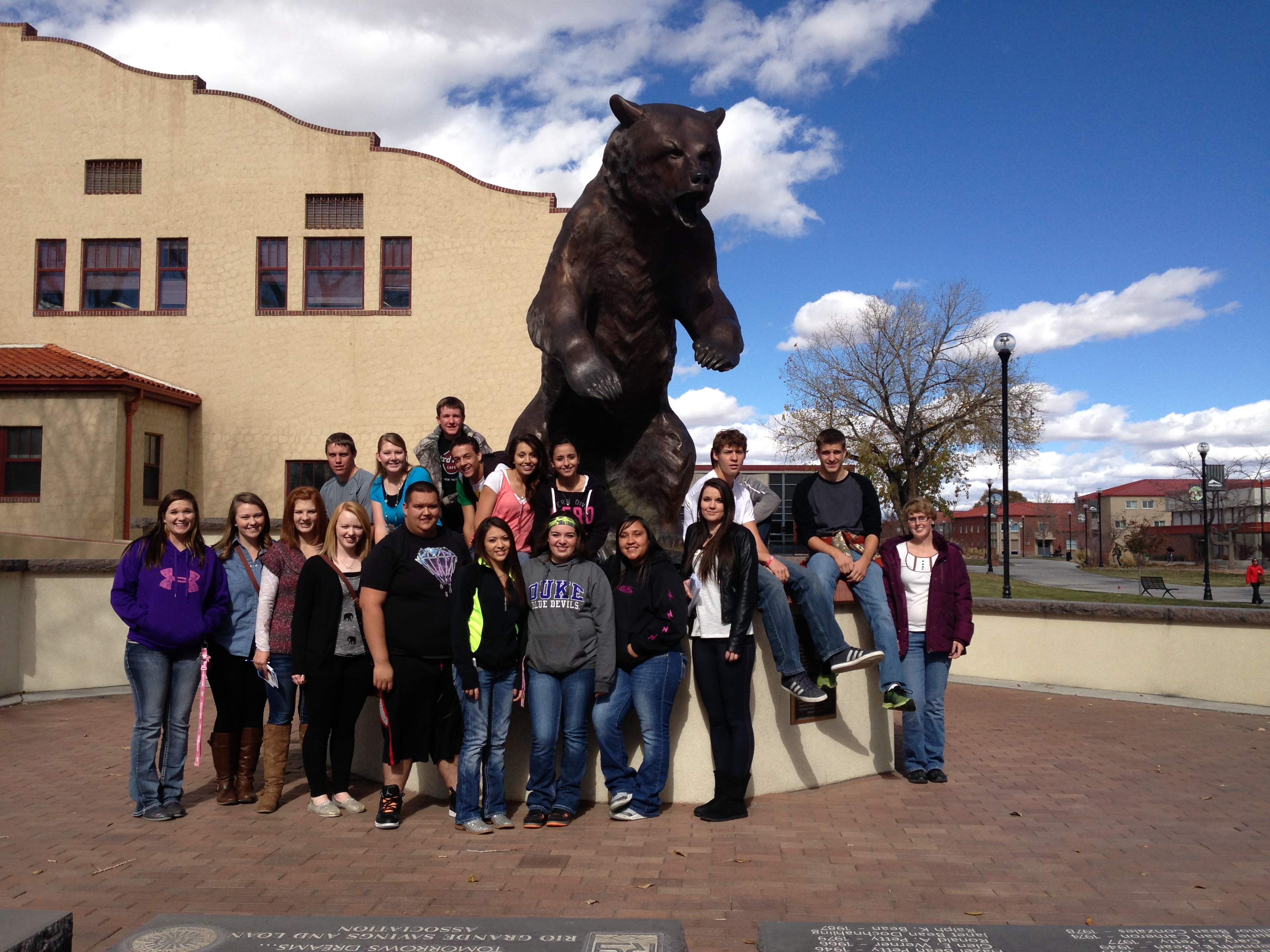 photo of a group of students in front of a bear statue