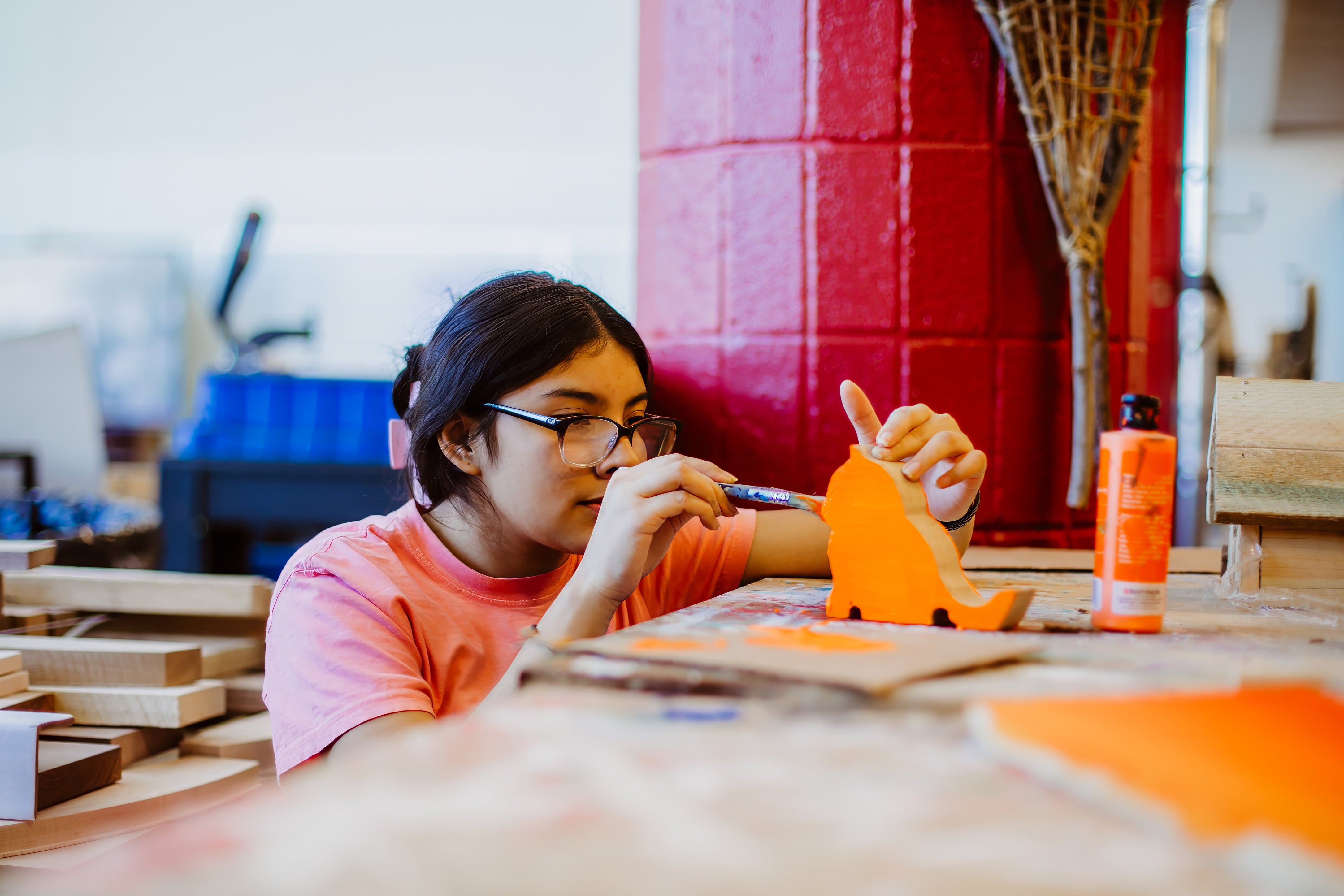 student painting a wooden bird