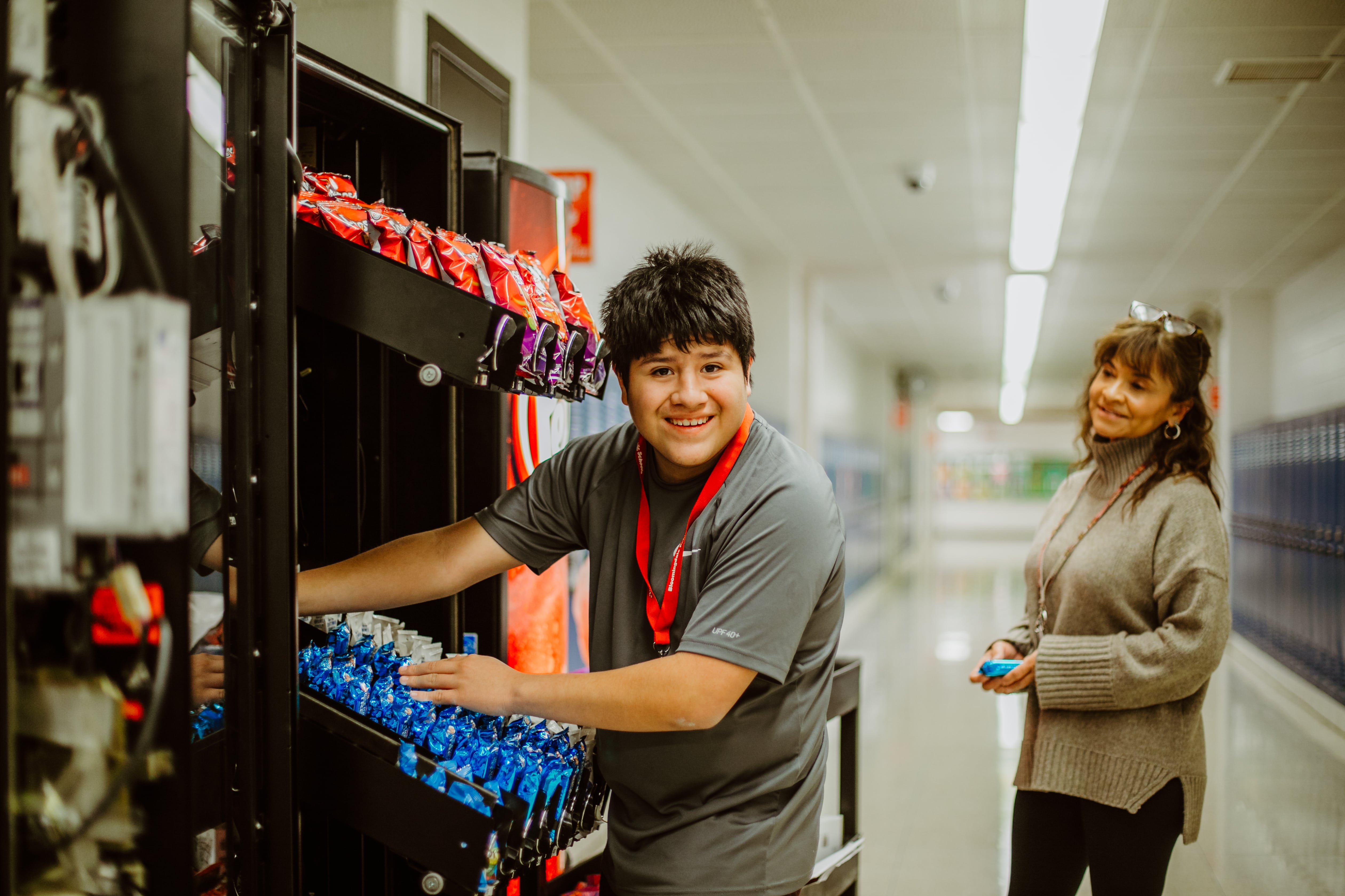 student filling vending machine with staff member