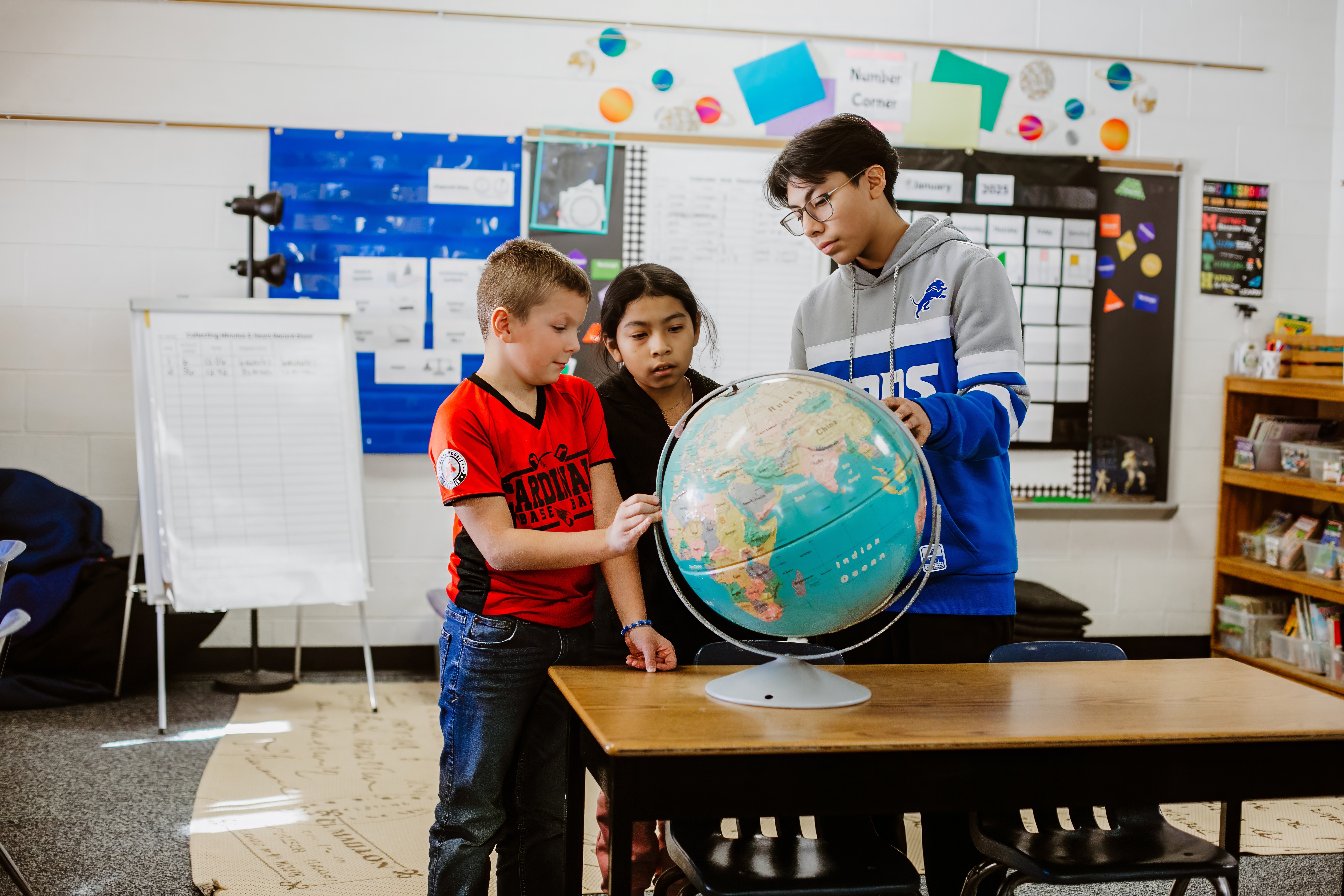 students looking at a globe in a classroom