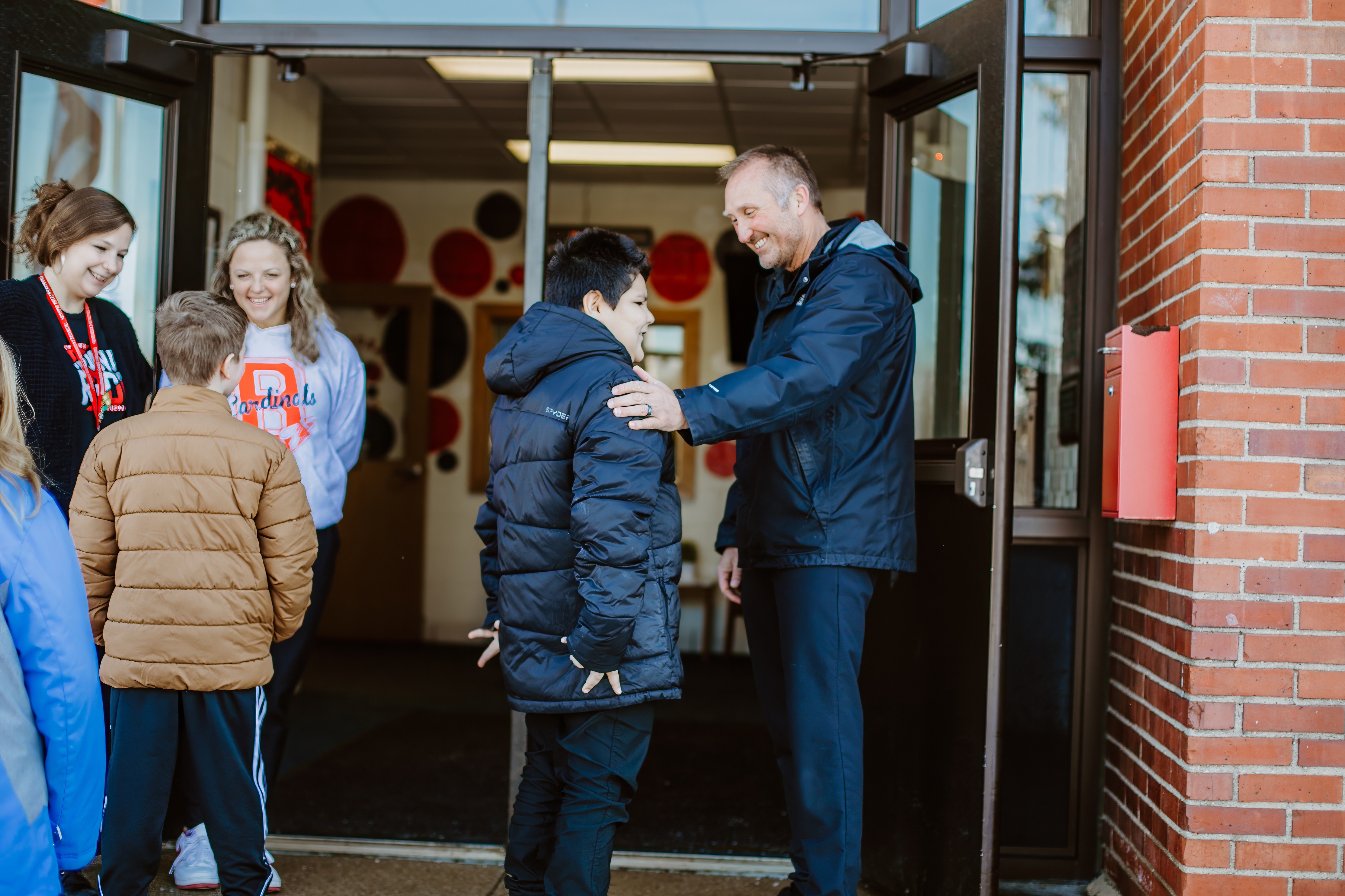 admin and staff greeting students at the door