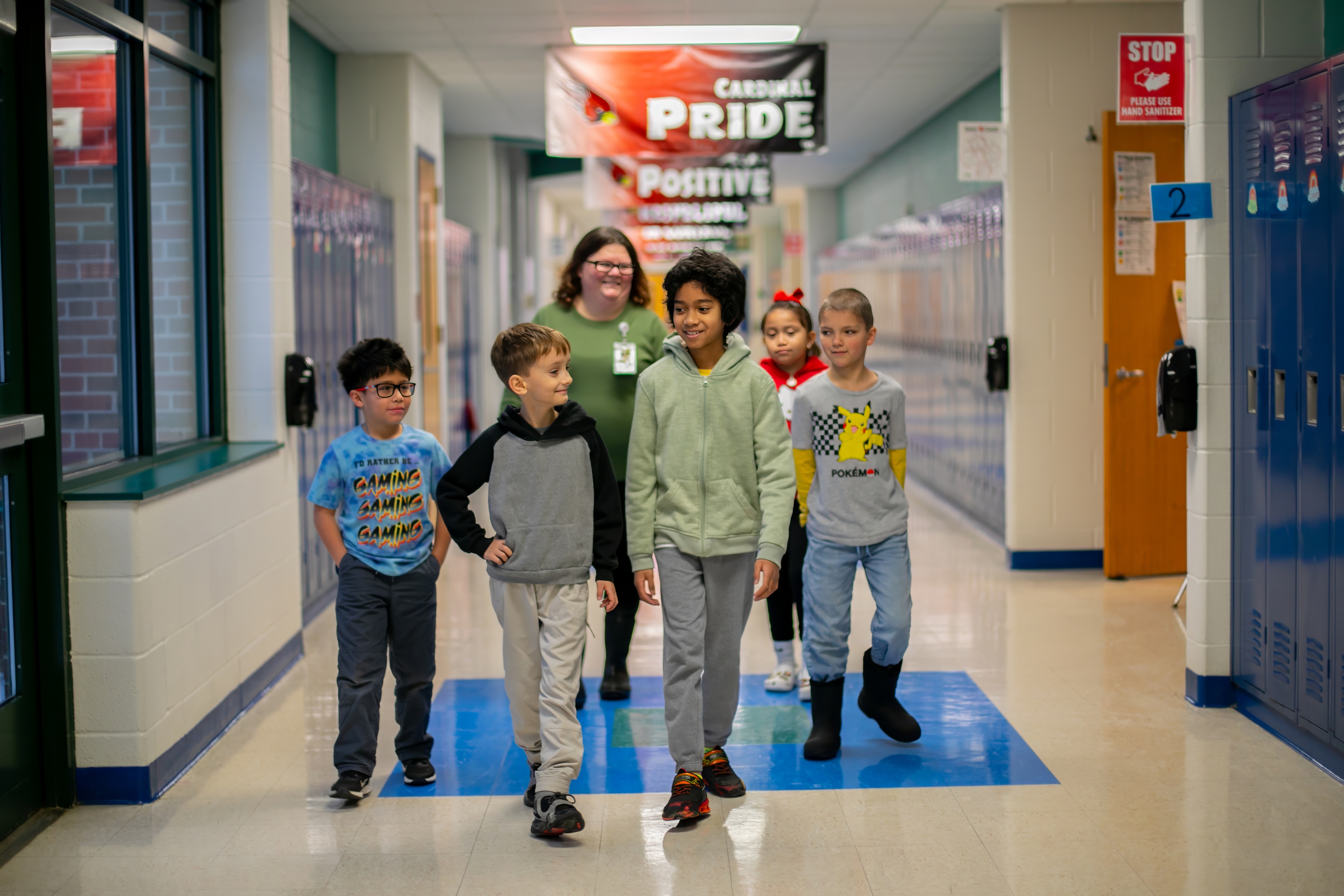 students and a staff member smiling in the hallway 