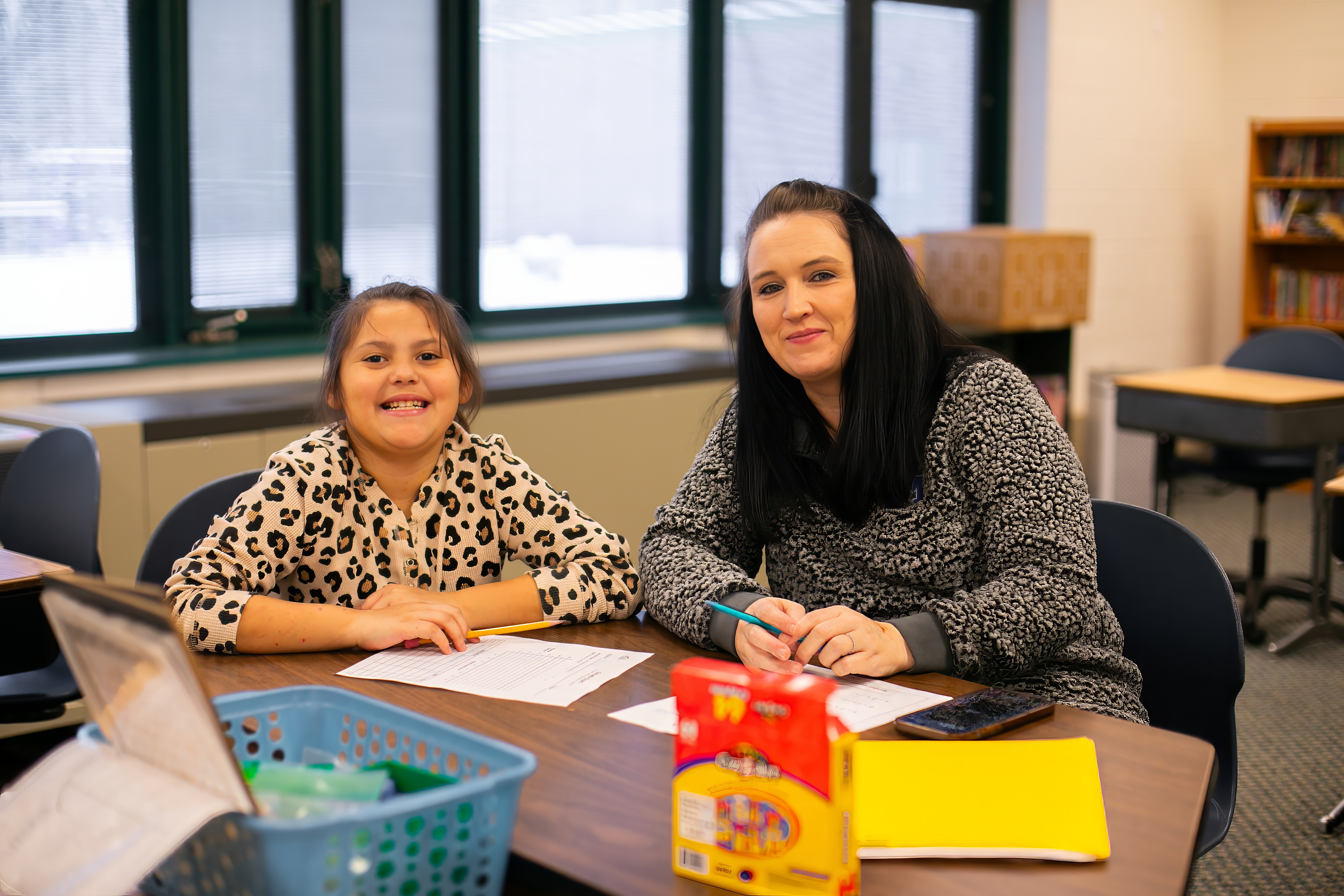 teacher and student smiling at at table 