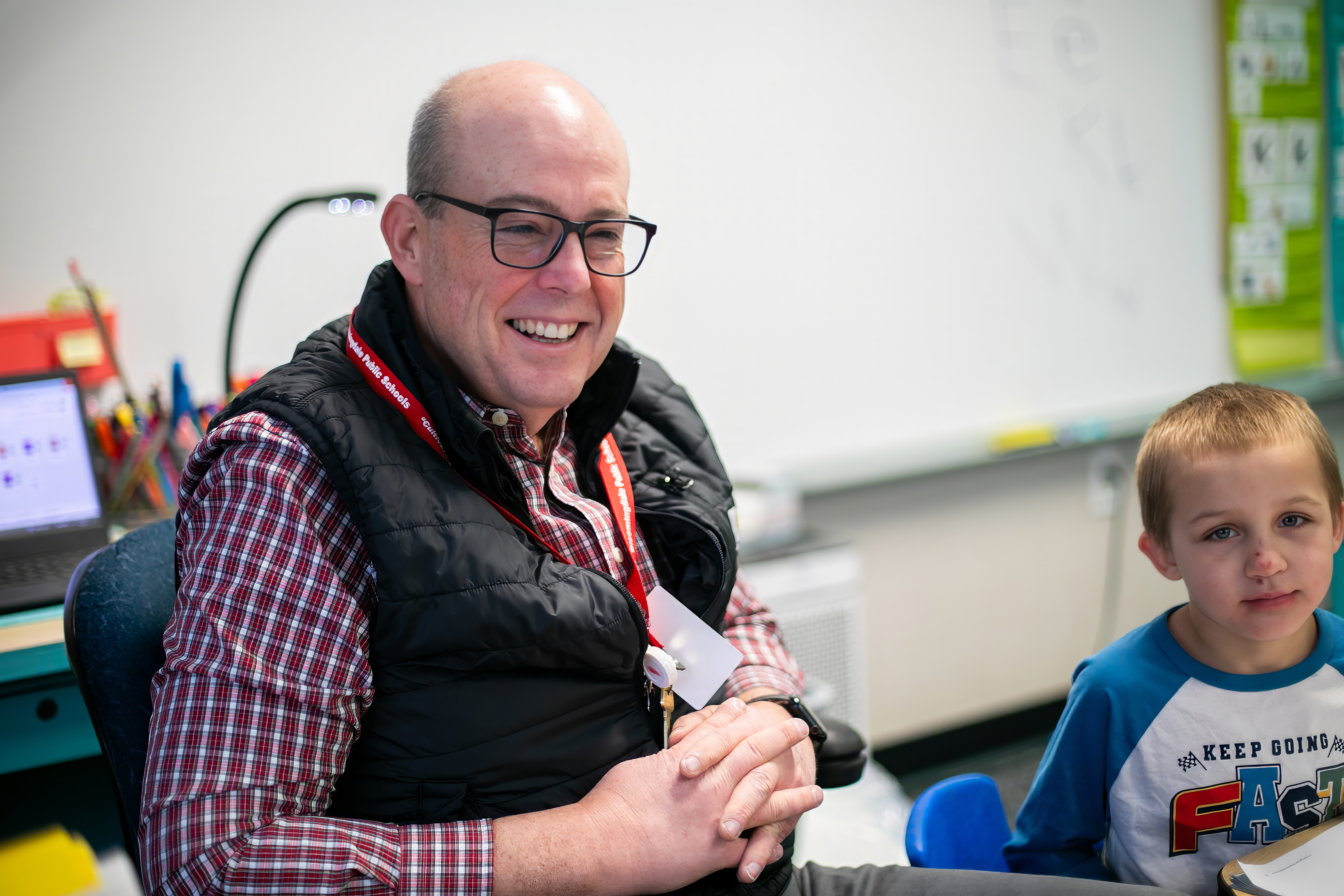 teacher smiling at. his desk 