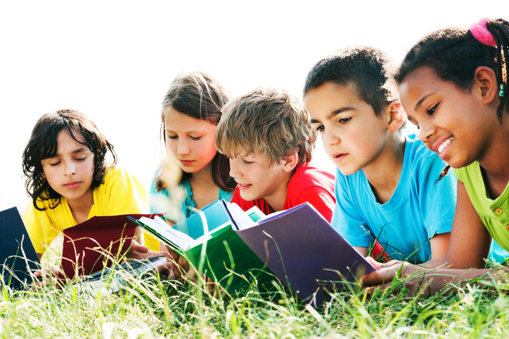 Children reading books on grass