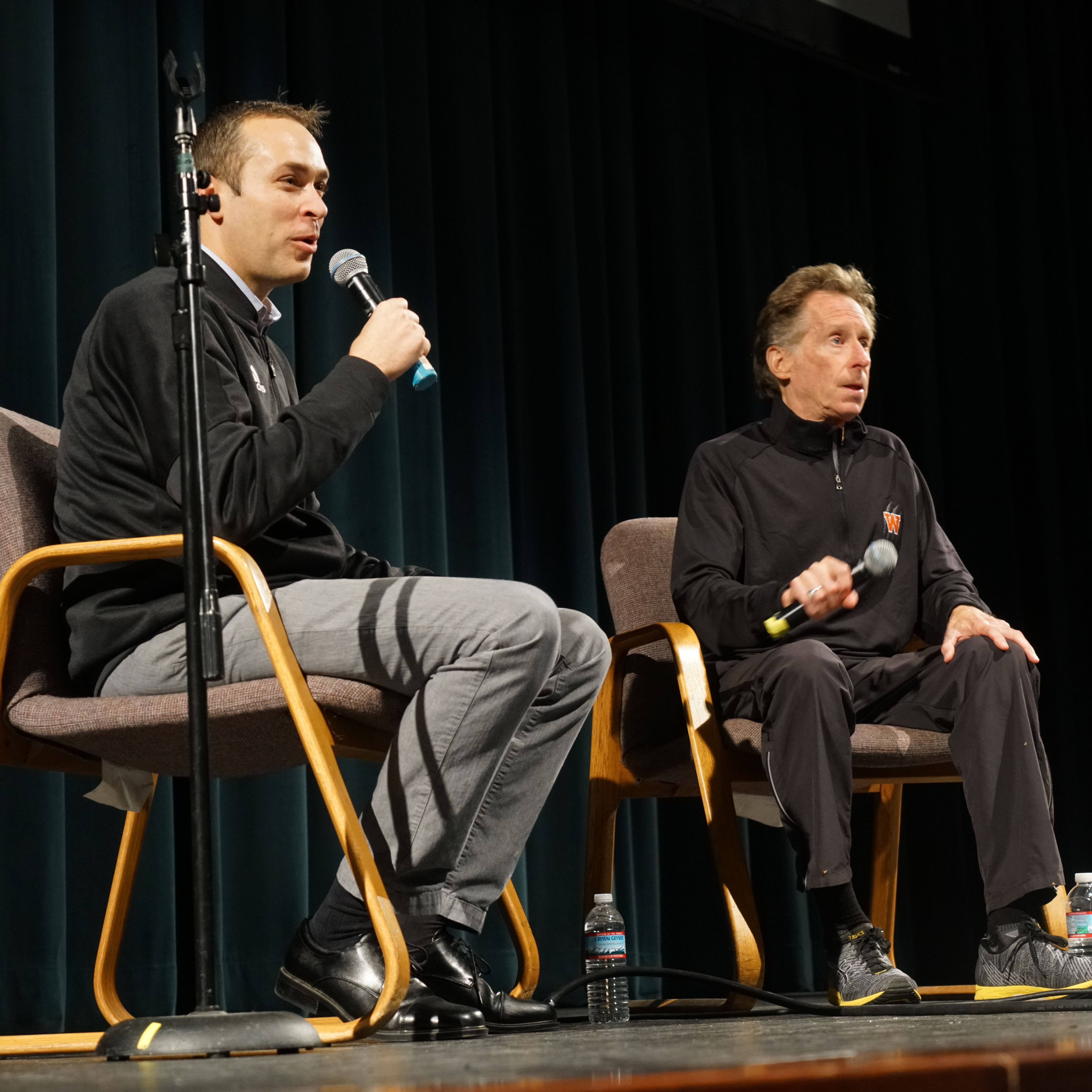 Presenters sitting in chairs on stage with microphones