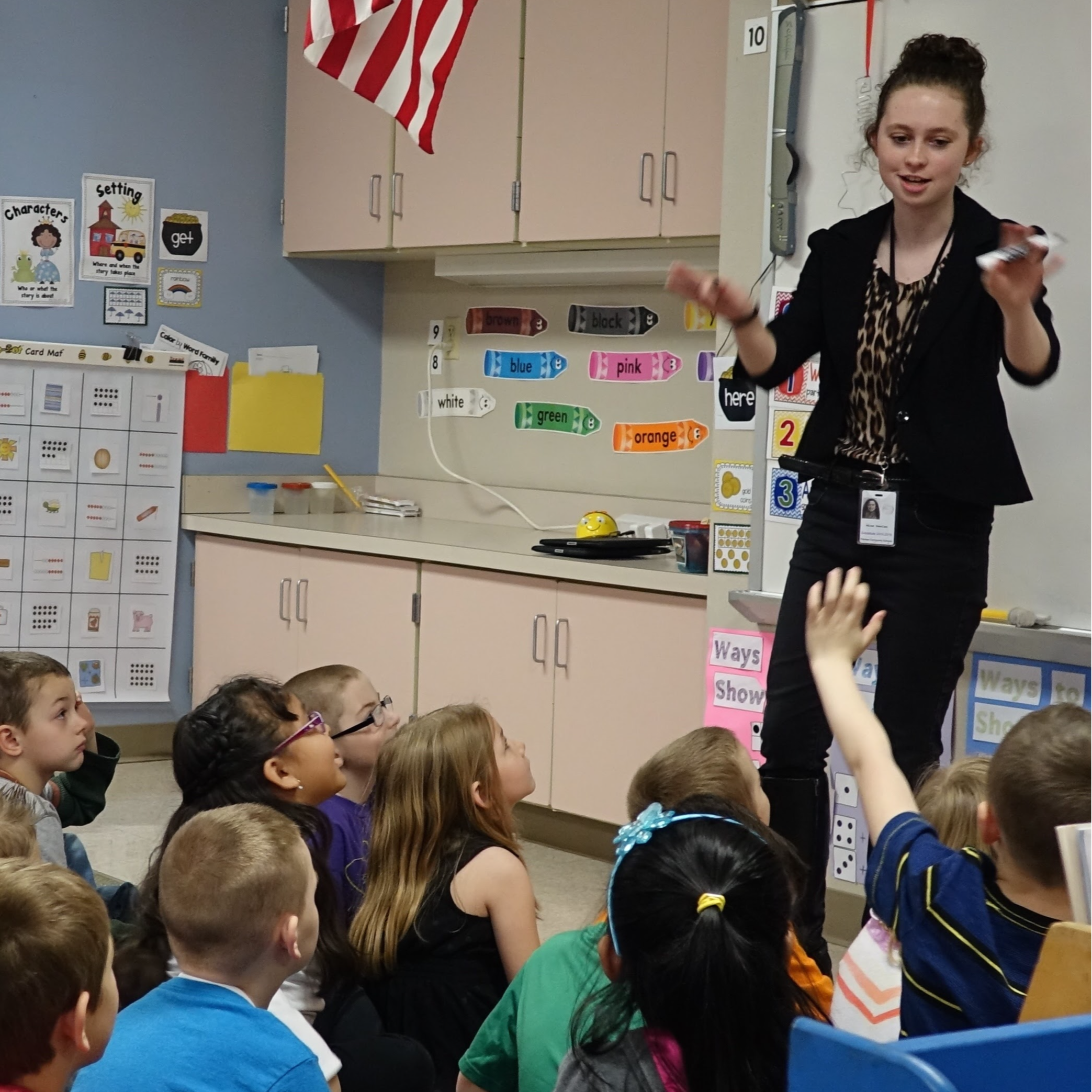 volunteer speaking to students seated on classroom floor