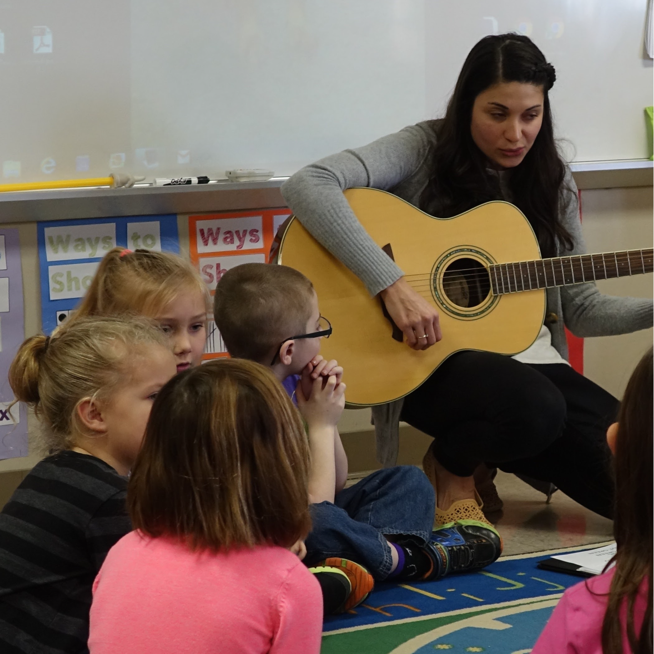 guitarist playing music for students seated on the floor