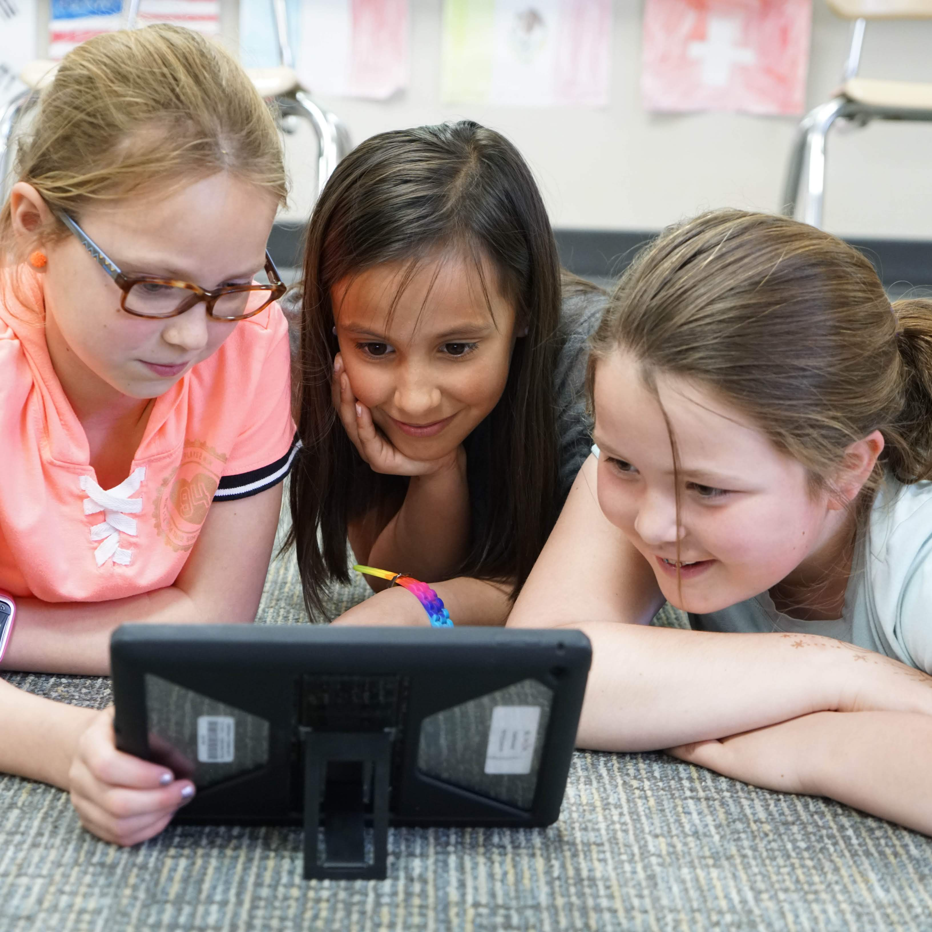 Students on floor watching content on instructional ipad