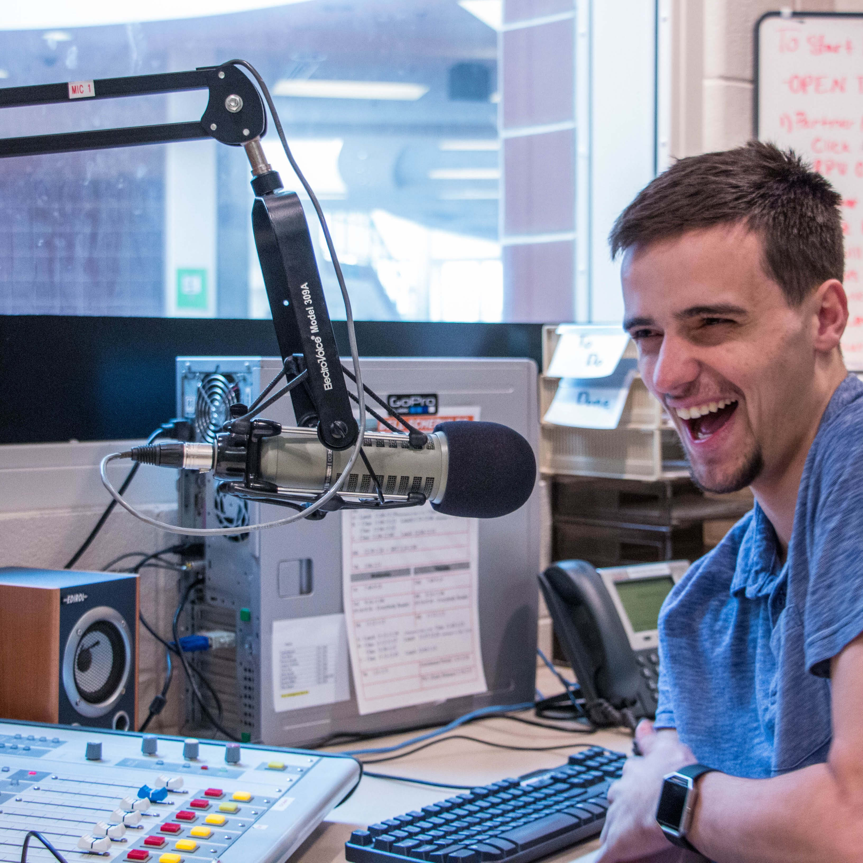 Student laughing next to microphone in a recording studio