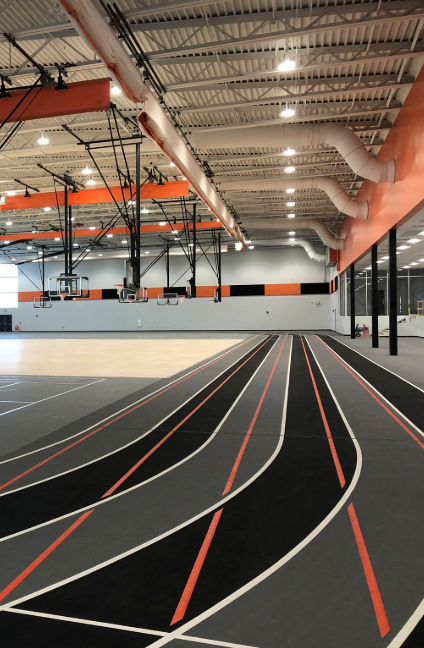 Student center track and basketball court with orange and black accents