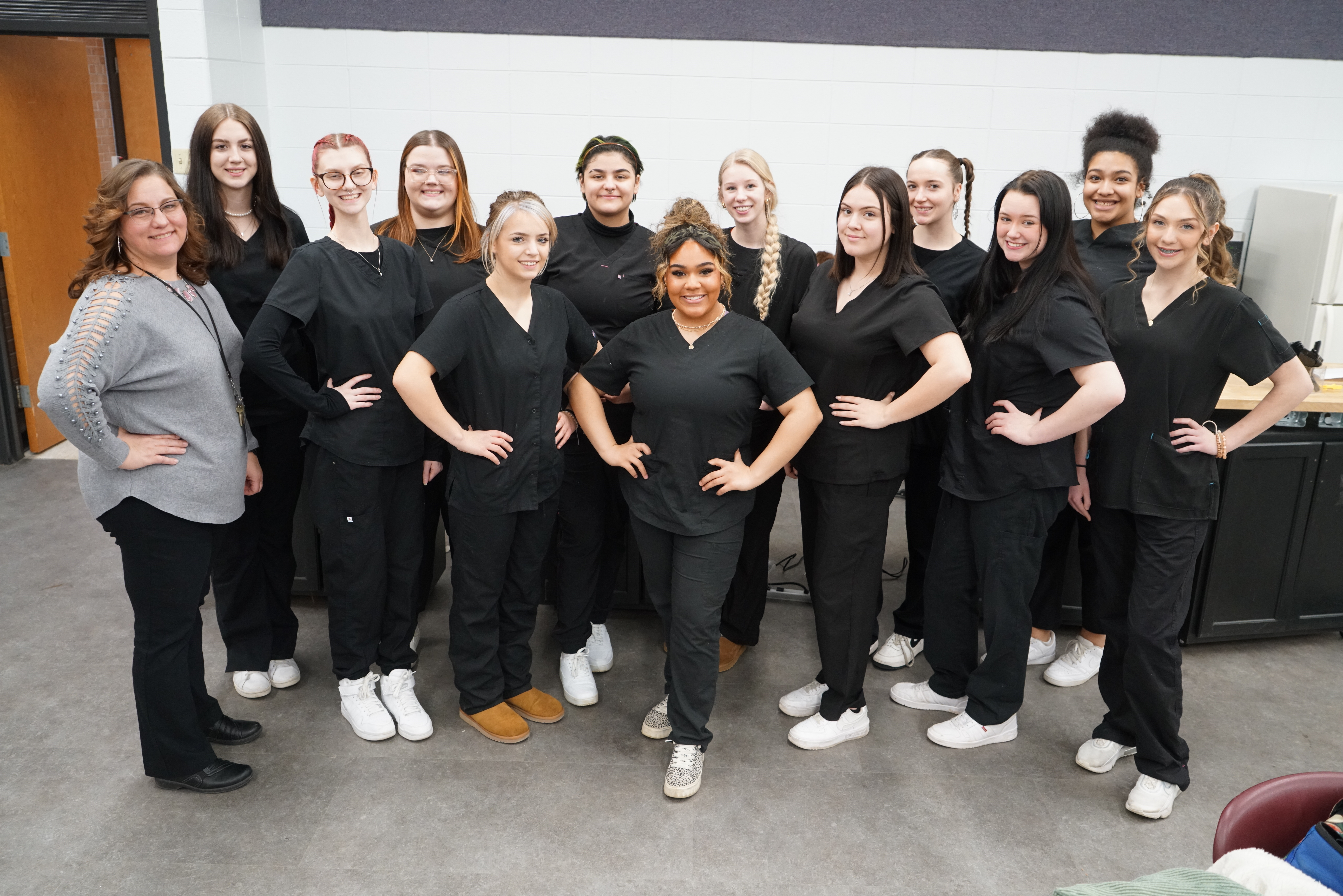 cosmetology preview; cosmetology students pose with hands on their hips in black scrubs