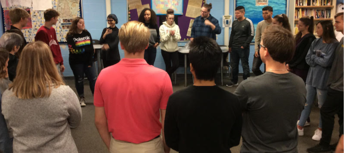 Students stand together in a circle in a classroom