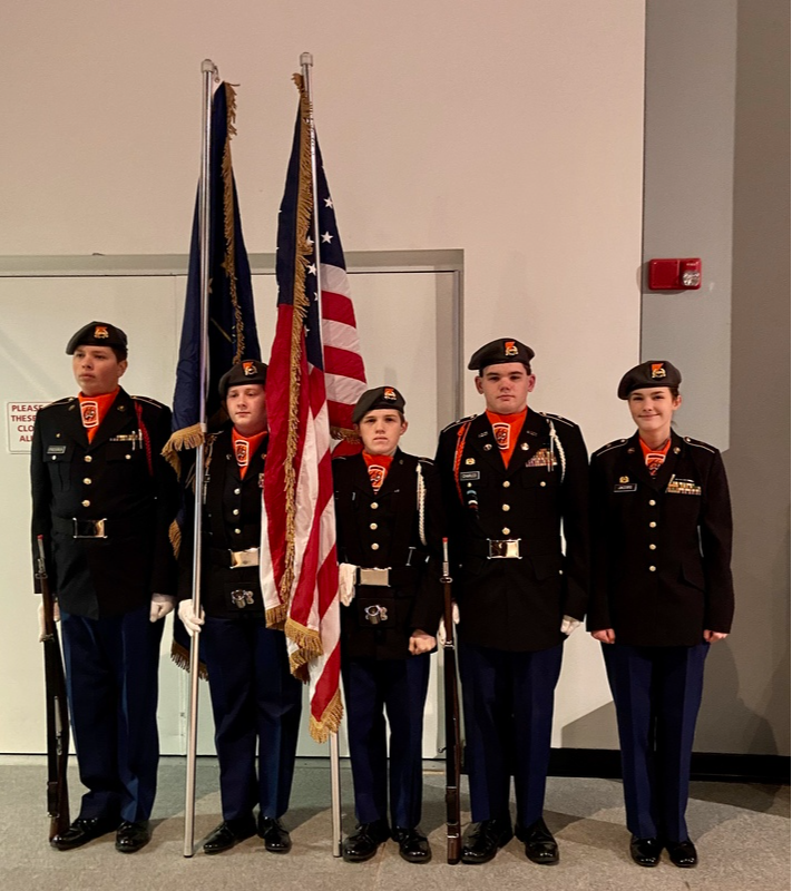 JROTC Members pose in uniform while holding flags