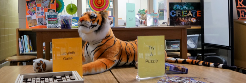 a stuffed tiger on a table with games and puzzles