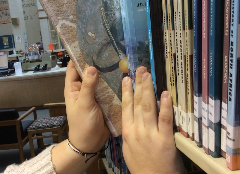 hands of a staff member pulling a book off a bookshelf