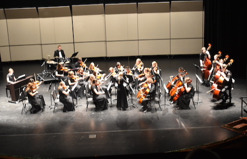 Orchestra students playing instruments on stage