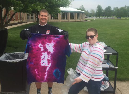 a student and mentor holding up a fresh tye dye shirt