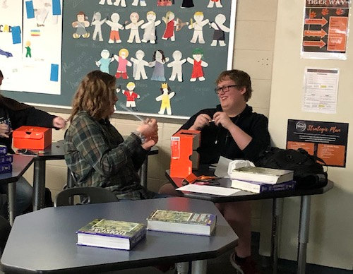 Students smiling and laughing as they work on decorating a shoe box together