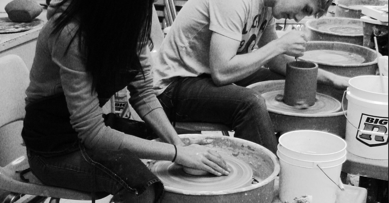 grayscale image of ceramic students working on pottery wheels