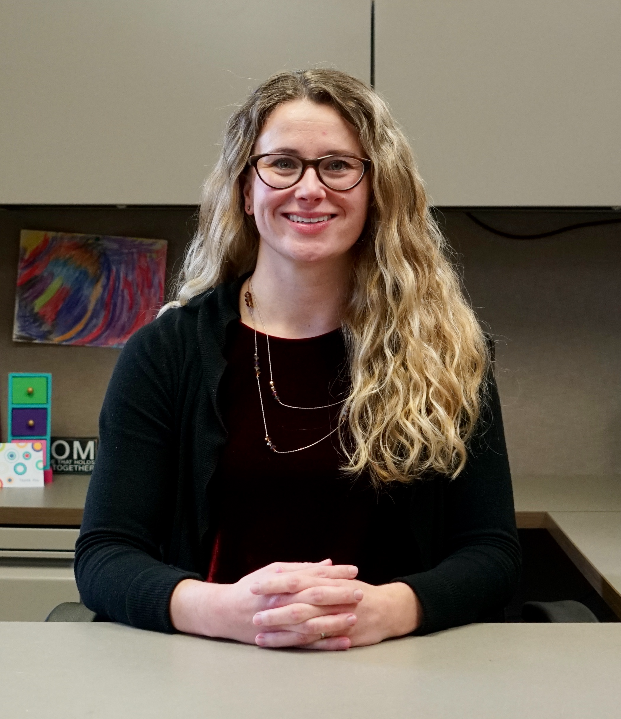 Sarah wallen, school counselor sits with hands clasped at her desk