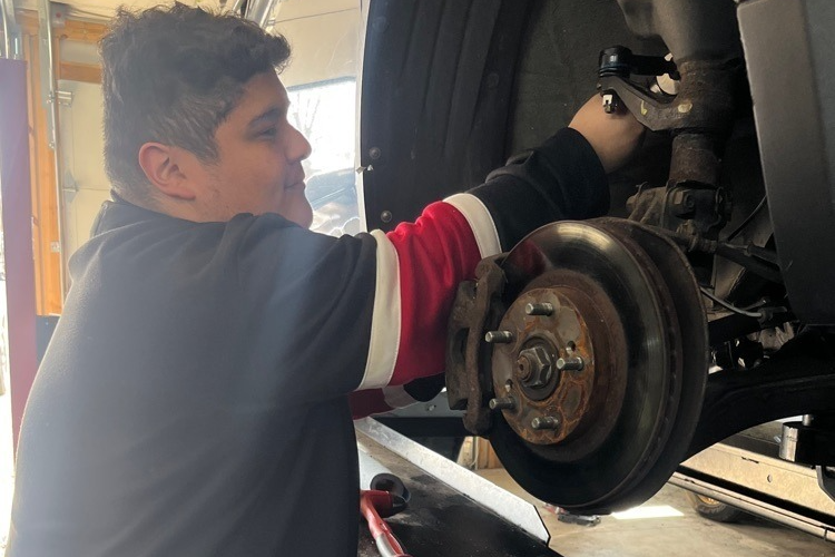 automotive student working on a vehicle's axel