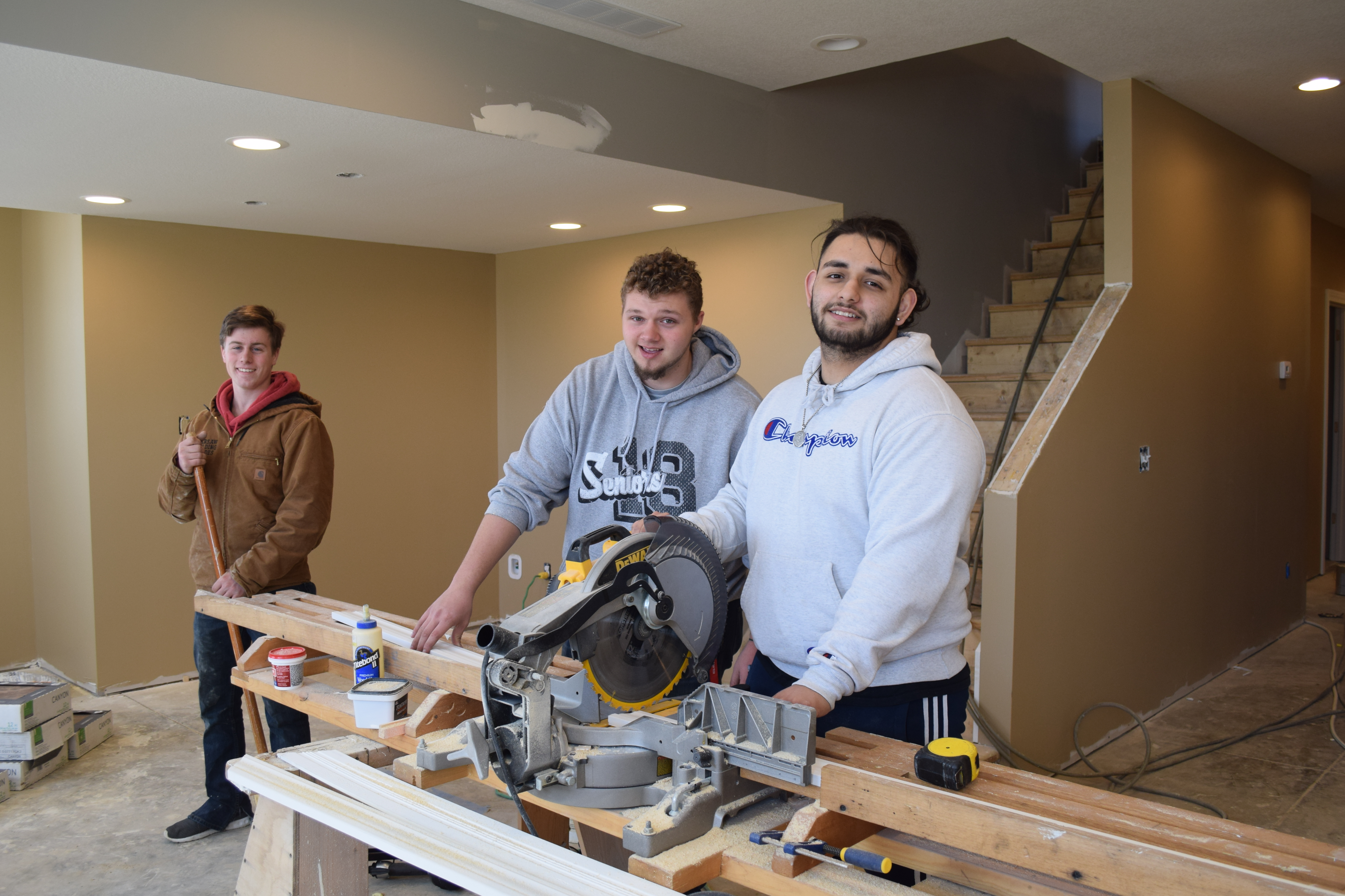 Building Trades Program students smile while they work with a skill saw 