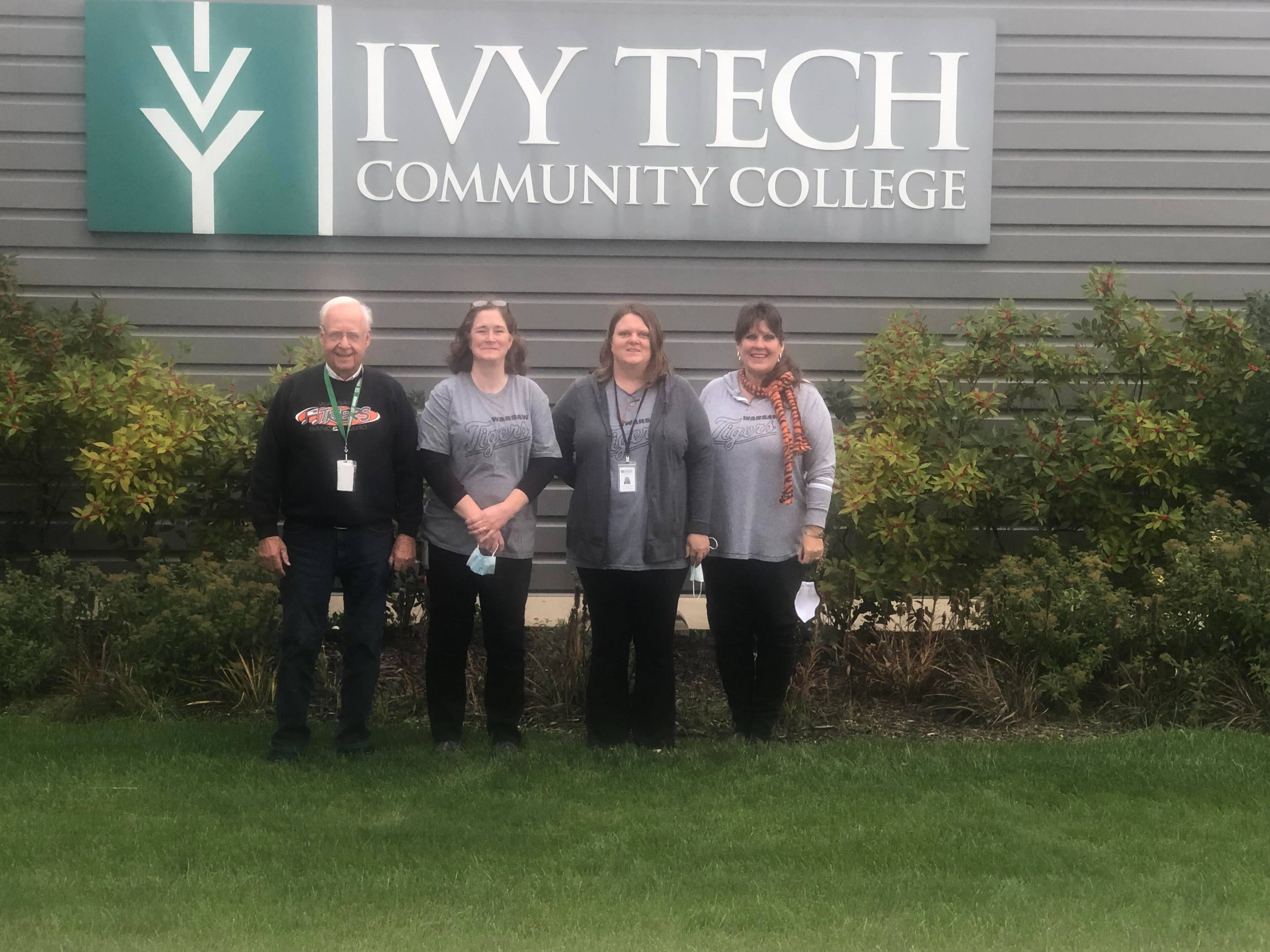 Warsaw adult education team posing below ivy tech community college exterior sign