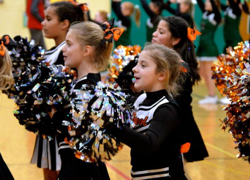 a group of young cheerleaders performing in the gym with their pom poms