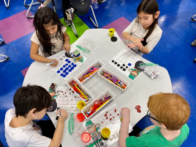 Students with markers at a table completing an assignment 