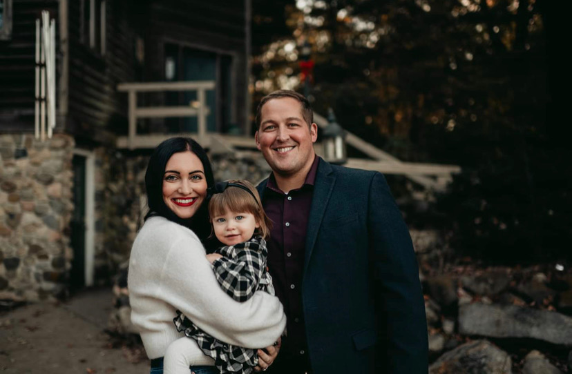 Principal Francesca Hoffmann holding her daughter, standing with her husband