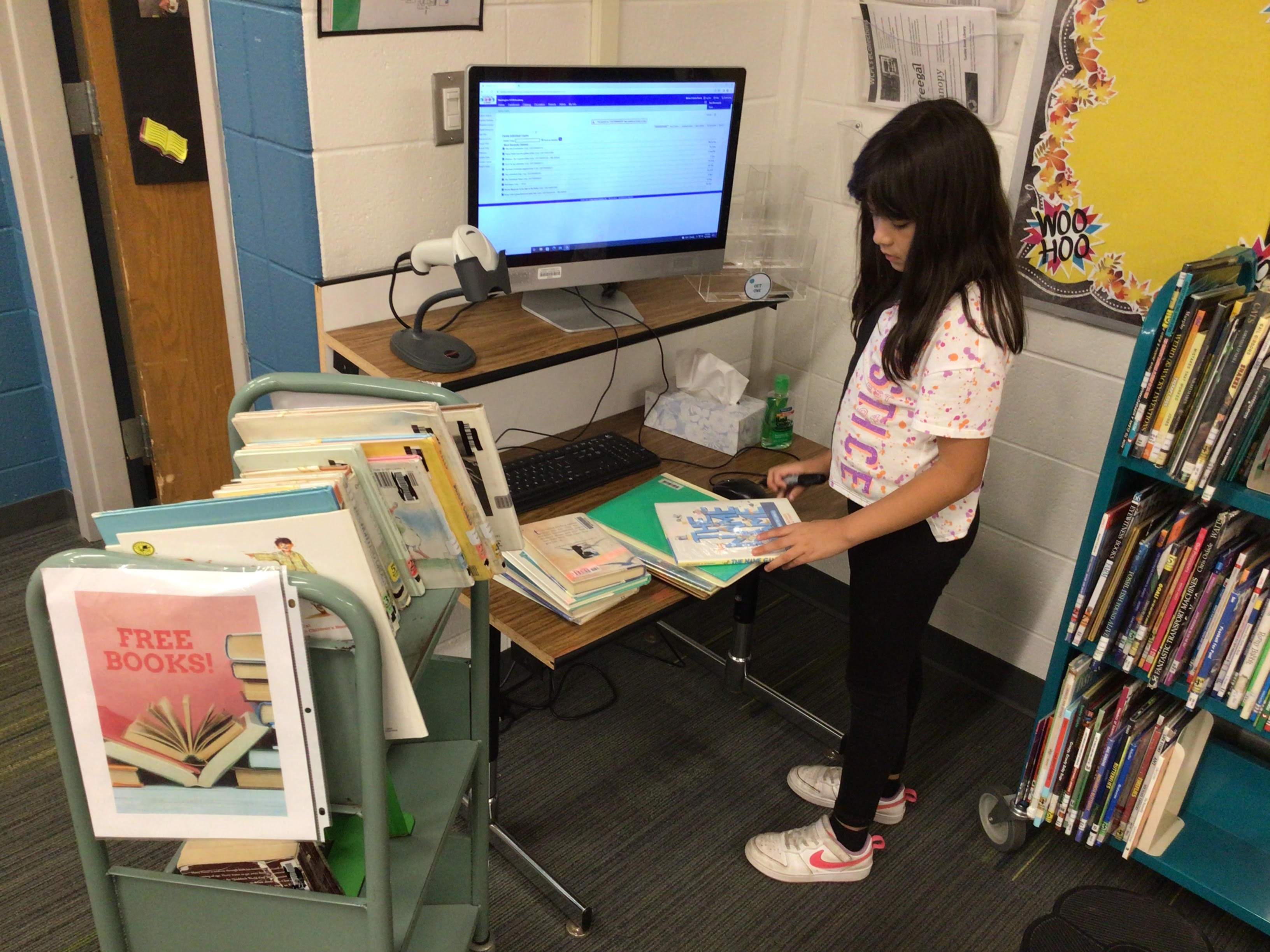 Student at the library computer surrounded by books