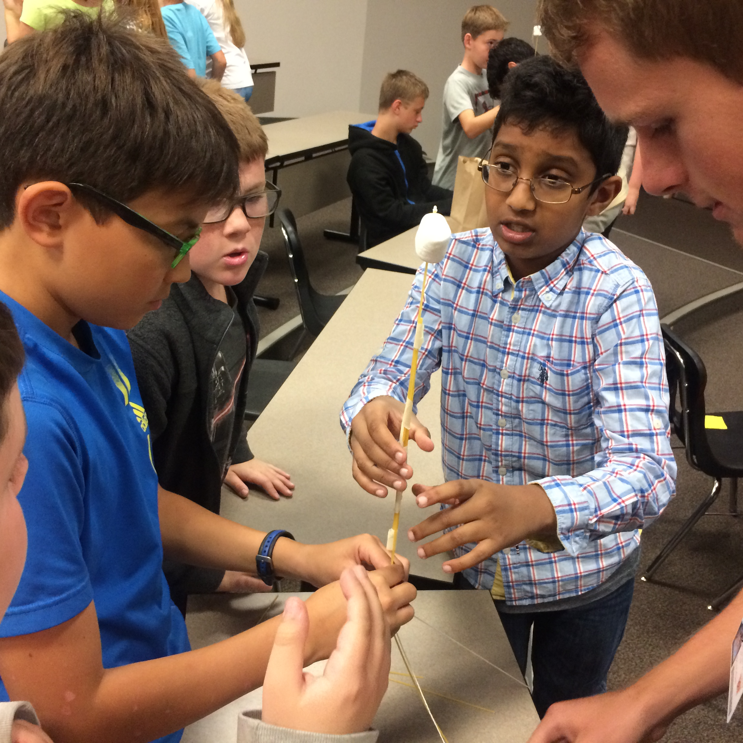 Students building a structure out of sticks and marshmallows 