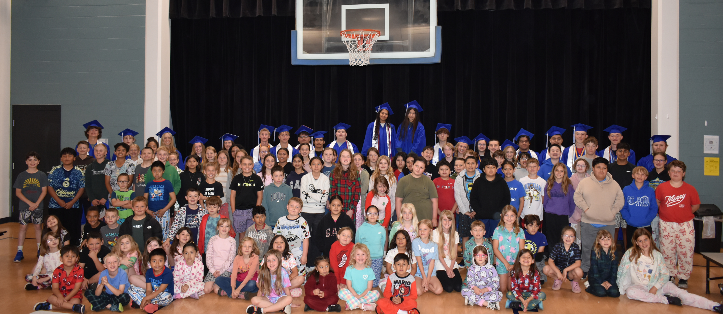 St. Paul High School graduating seniors with the elementary school students in the multipurpose room.
