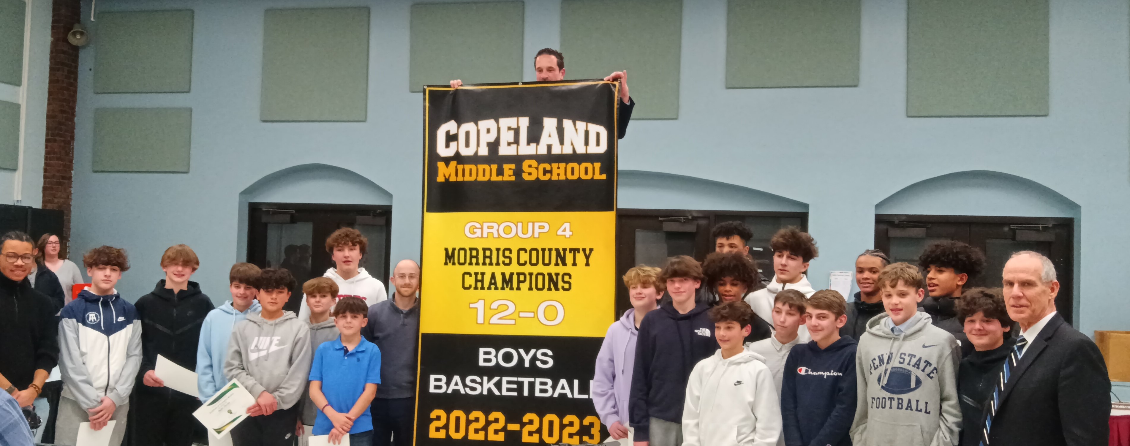 Dr. Corbett standing with students and staff recognizing the Boys Basketball 2022-2023 Morris County Championship