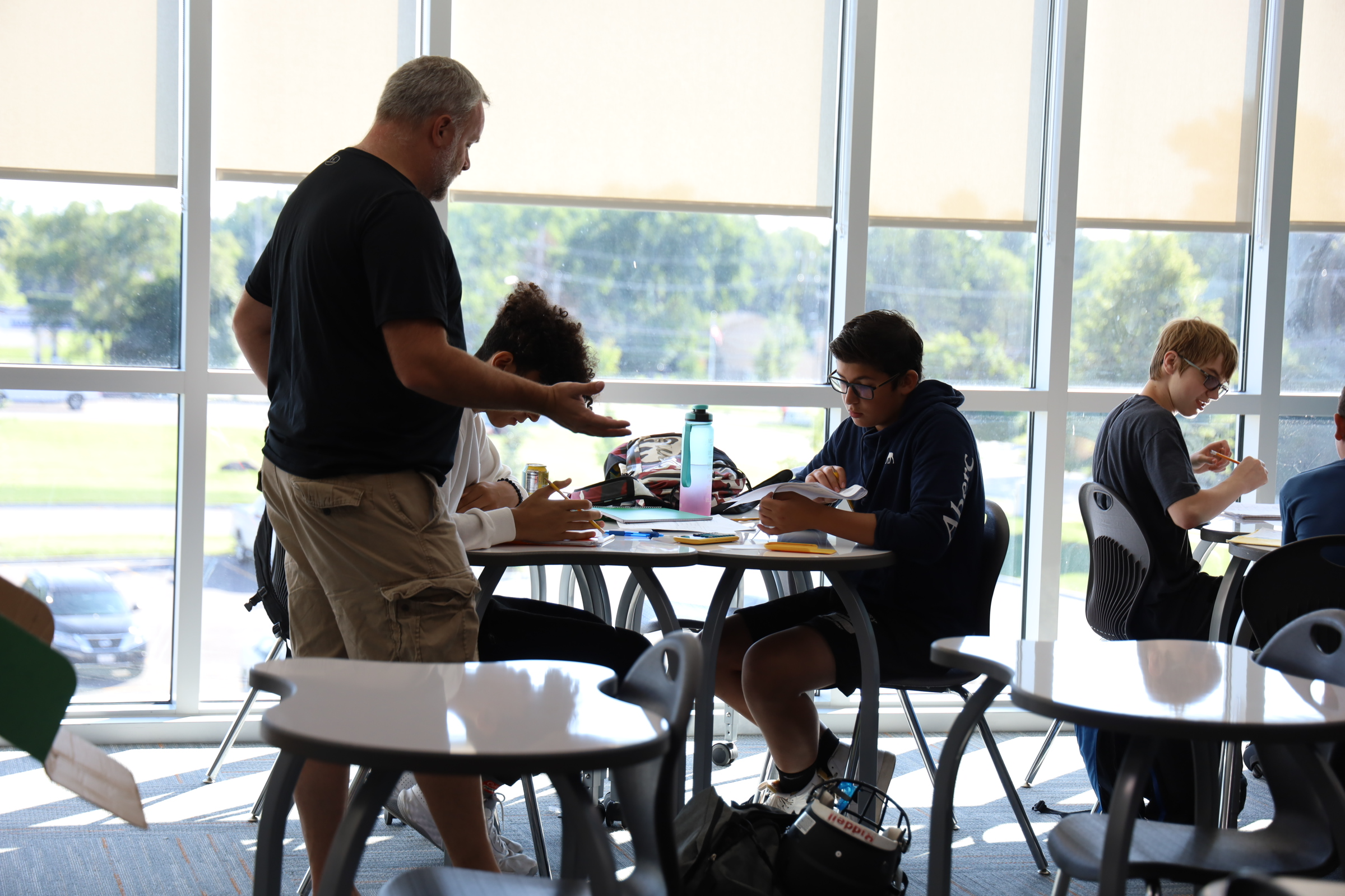 A teacher helping two students at their desks