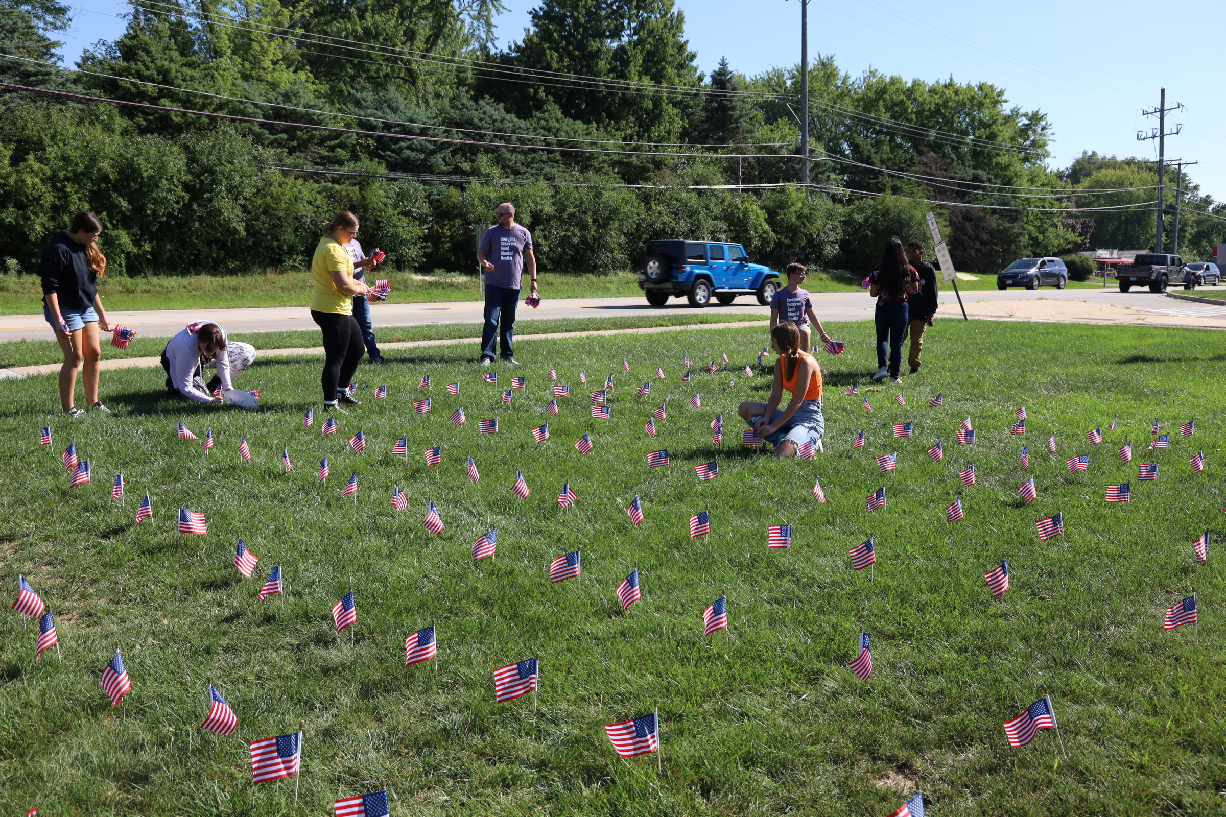 Students setting up American flags in the grass for 9/11