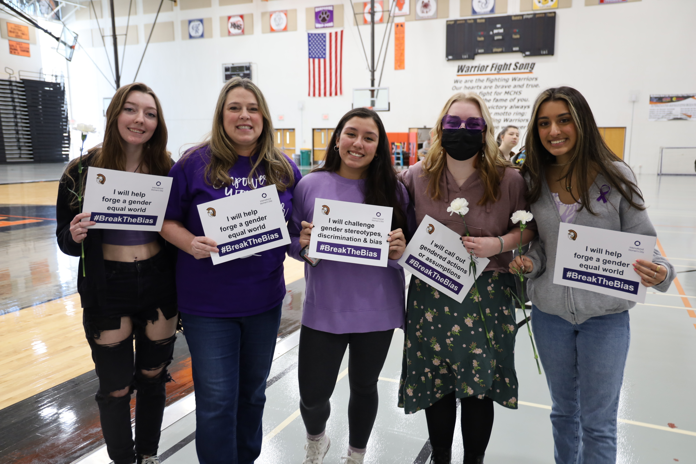 Students and teacher with women's day signs: "I will help forge a gender equal world." I will challenge gender stereotypes, discrimination and bias."I will call out gendered actions or assumptions." "I will help forge a gender equal world."