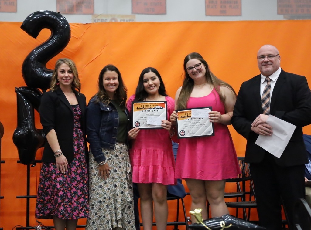 Three adults with two students holding scholarship awards