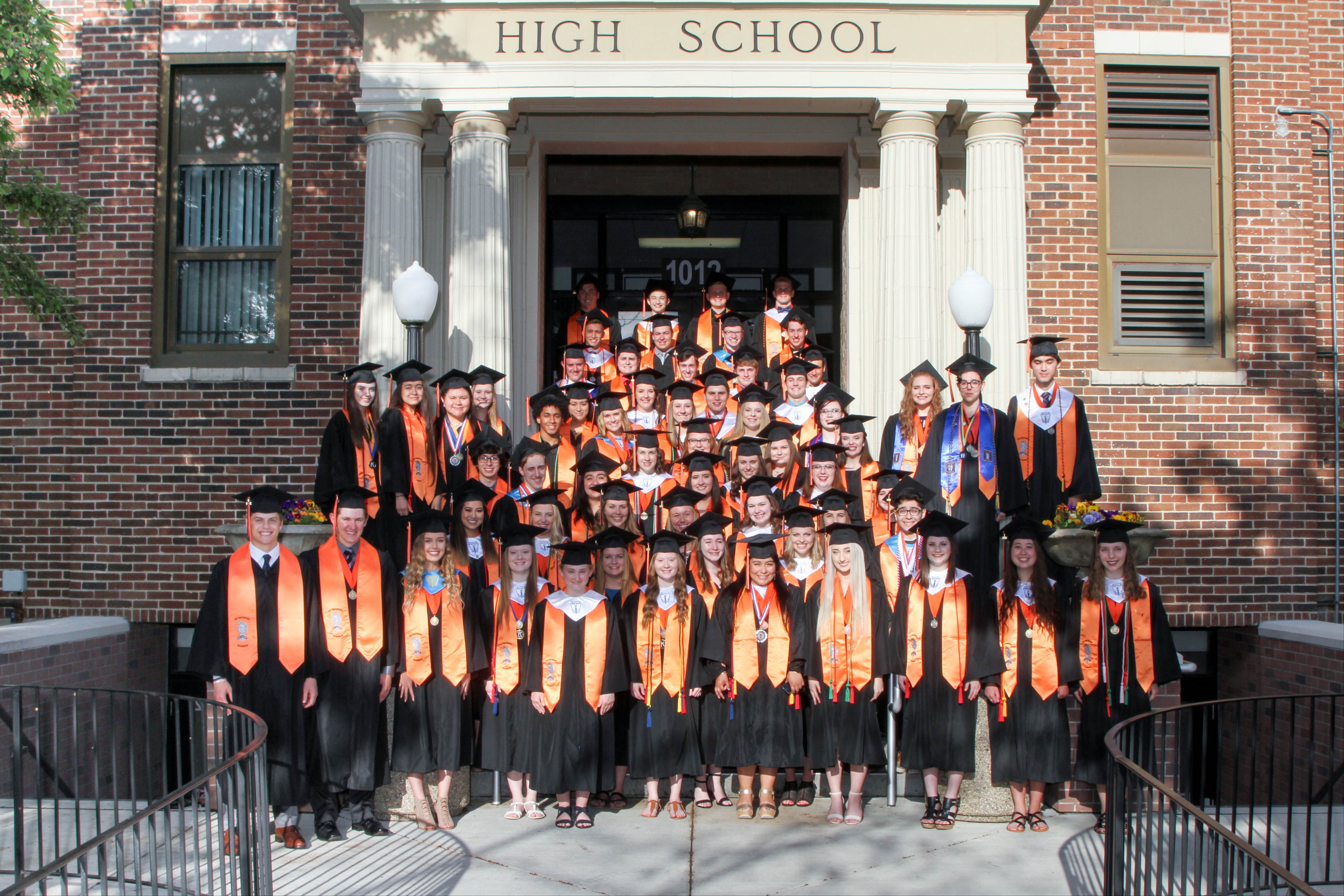 Class of 2018 East Campus Distinguished Warriors in stoles and caps and gowns in front of East Campus