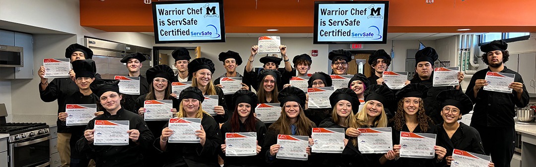 Students in chef uniforms holding their certificates