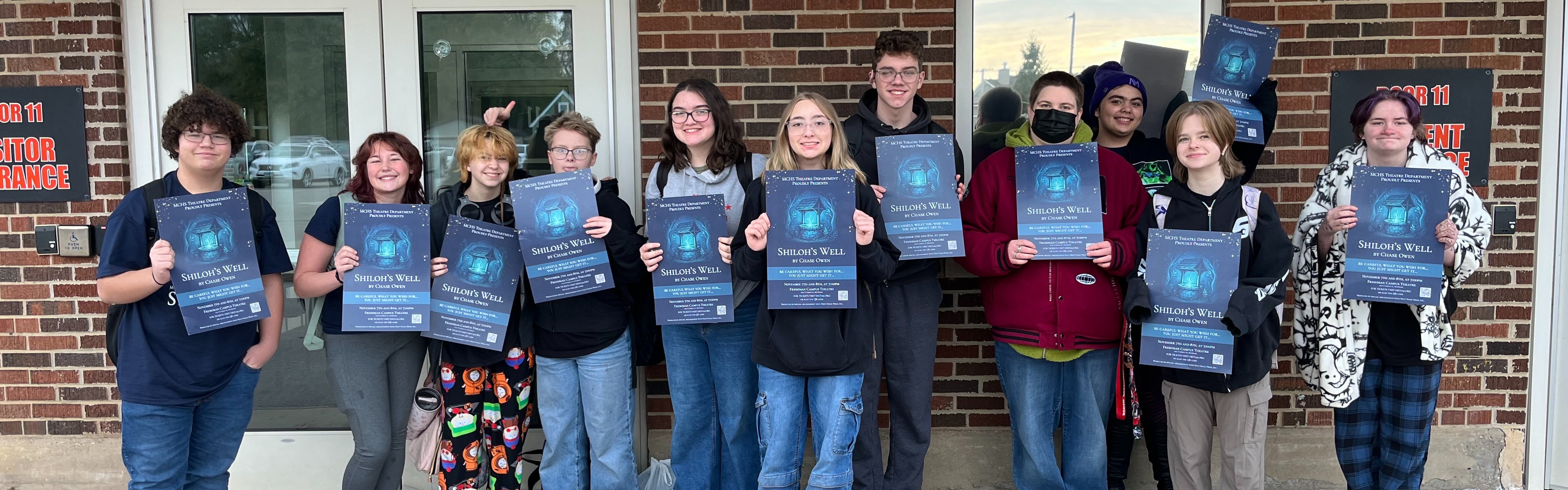 Group of students holding fall play poster