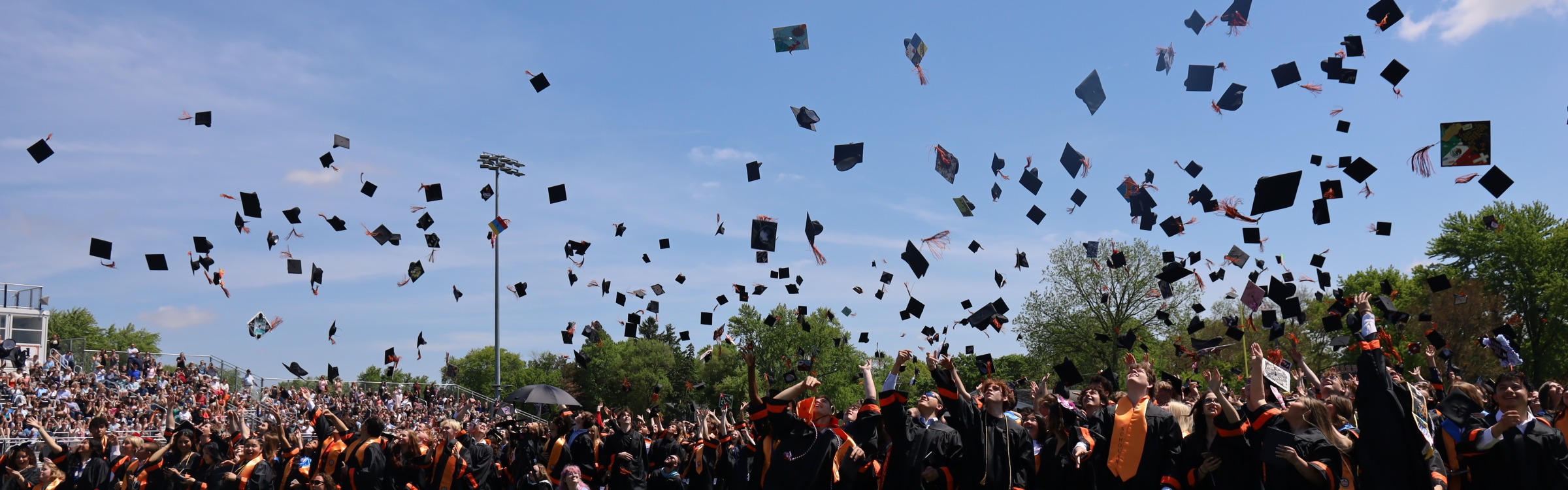 Graduates throwing caps at graduation on the football field