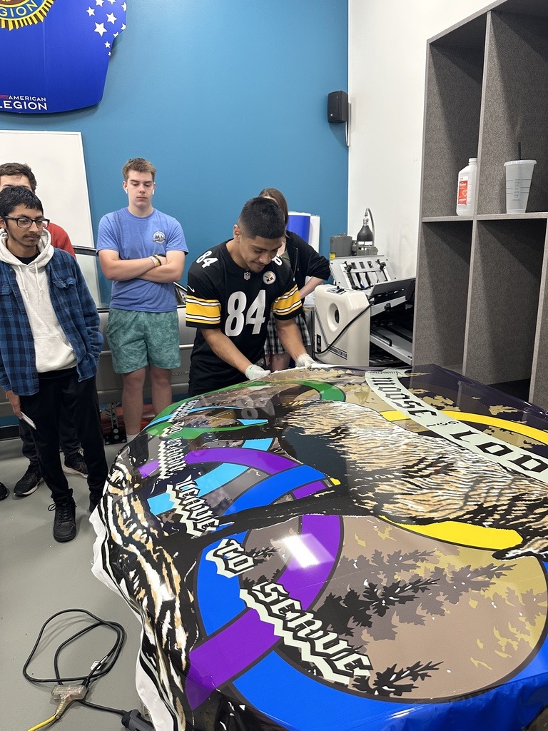 Graphics students with a car wrap on a hood